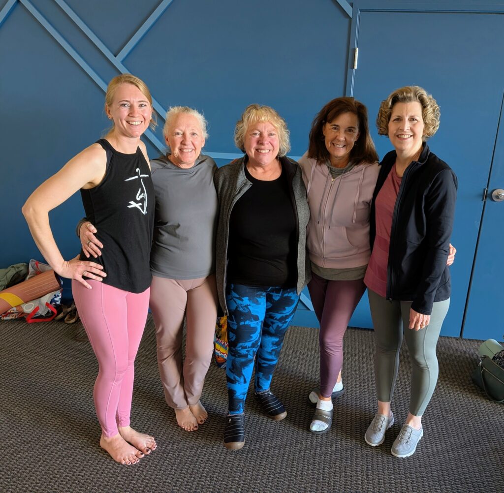 Sarah with four yoga students and all are smiling.
